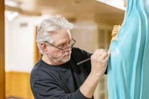 Man paints a statue of the blessed mother. Photo by Brian Keith.