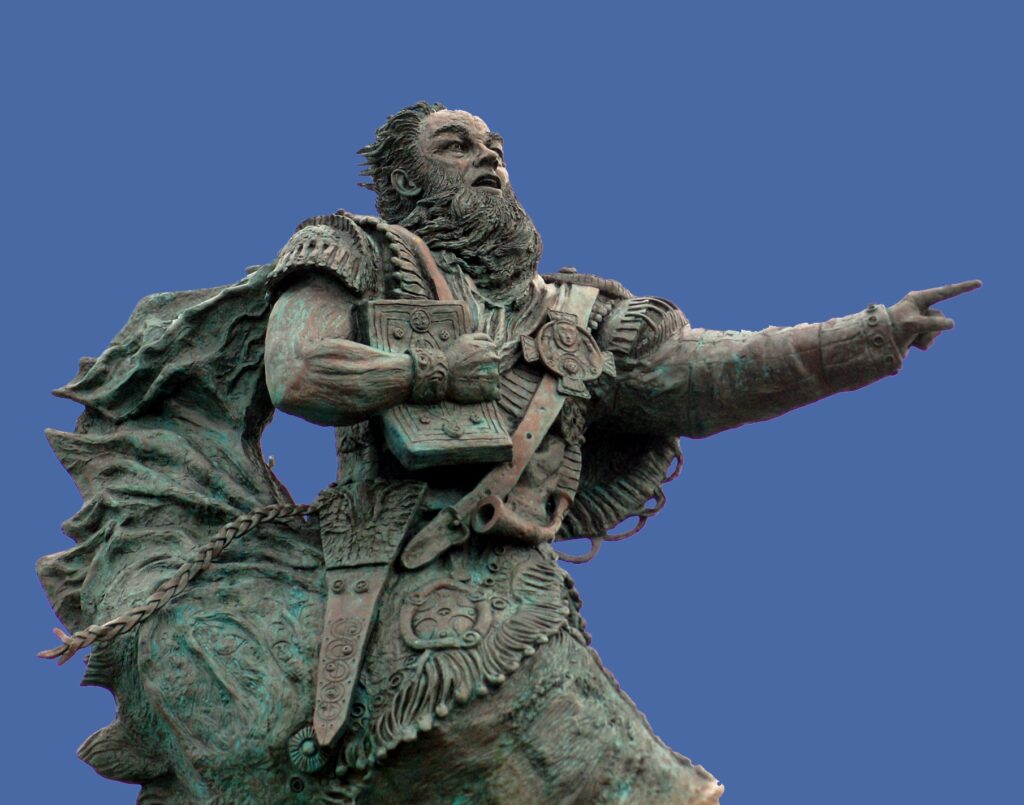 Bronze statue of St. Brendan, pointing toward the sea.
