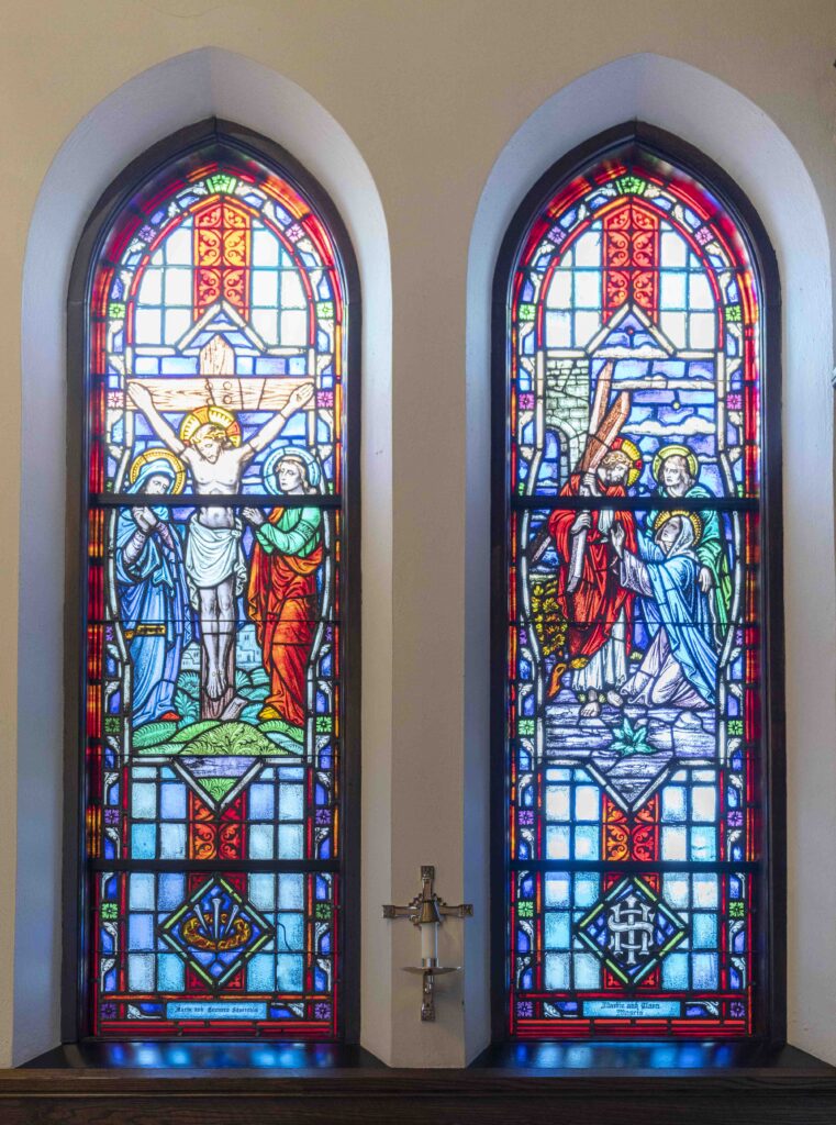 Two stained-glass windows. On the right, Jesus carries his cross and on the left he is Crucified. Located at Immaculate Conception Parish in Ravenna. Photo by Brian Keith.