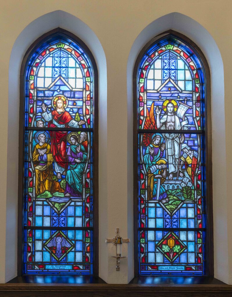 Two stained glass windows. In the window on the left, Jesus ascends. In the window on the right, Jesus stands above his tomb. Located at Immaculate Conception Parish in Ravenna. Photo by Brian Keith.