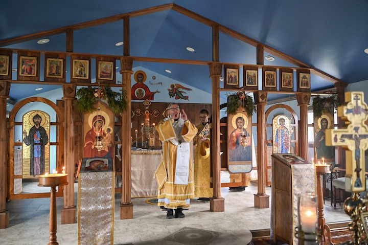 Image of priest standing at an ornate altar in a gold vestment