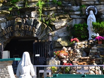 Image of the shrine with a nun in a white habit praying before it.