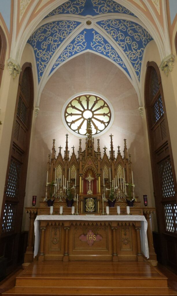 Image of altar in front of rose window with blue, night sky-painted vaulted ceiling