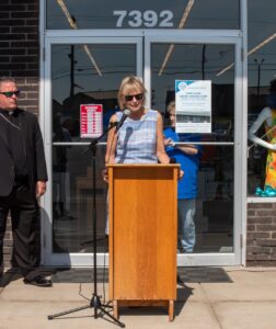 woman speaks at a podium outside a st. vincent de paul thrift store. photo by courtney poullas.