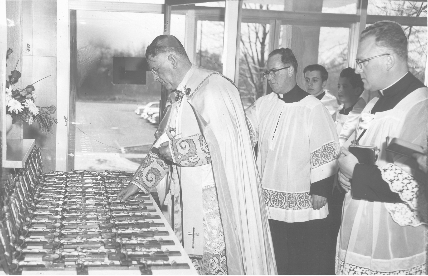 Bishop Walsh, with three priests behind him, blesses crucifixes at the new hospital