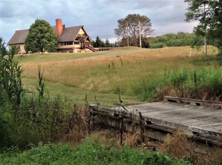 Image of a barn on a hillside, with a bridge leading up to it