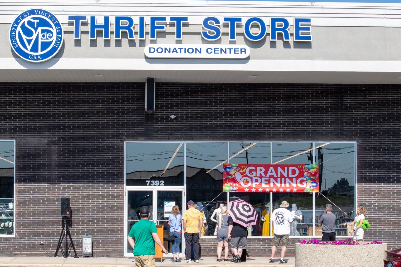 Image of people gathering outside a St. Vincent de Paul thrift store with a "grand opening" banner. Photo by Courtney Poullas.