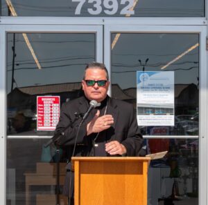 Bishop Bonnar with his hand over his heart outside a St. Vincent De Paul thrift store, at a podium. Photo by Courtney Poullas.