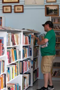 Man in a green shirt peruses books at a St. Vincent de paul thrift store. Photo by Courtney Poullas