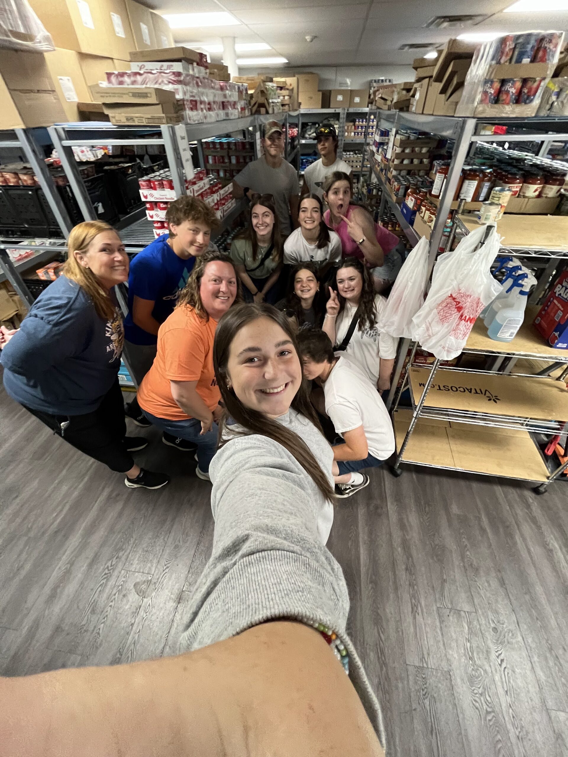 a group of young adults take a selfie in a storeroom.