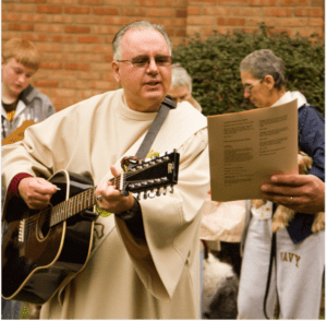 Man in vestment, playing guitar outside