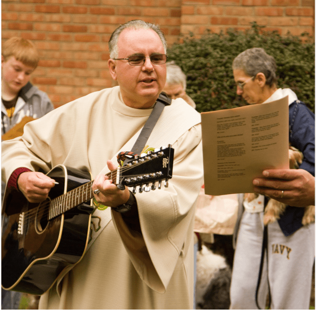 Man in vestment, playing guitar outside