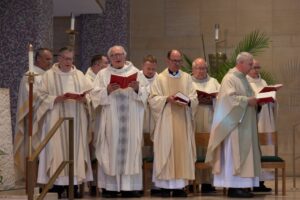 Several priests and bishops stand, holding hymnals. Photo by Courtney Poullas