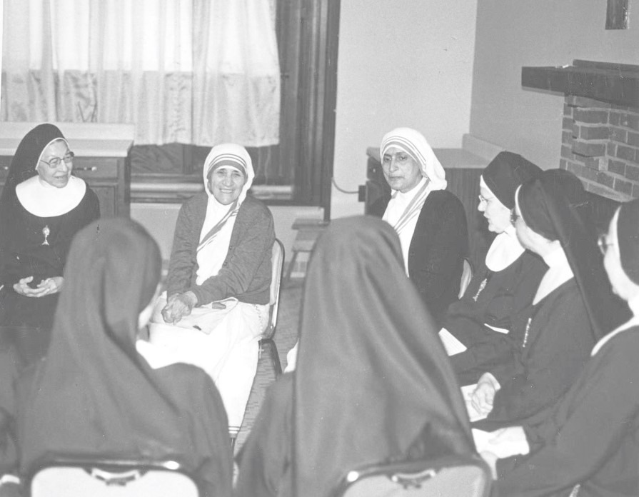 Black and white image of Mother Teresa, surrounded by religious sisters