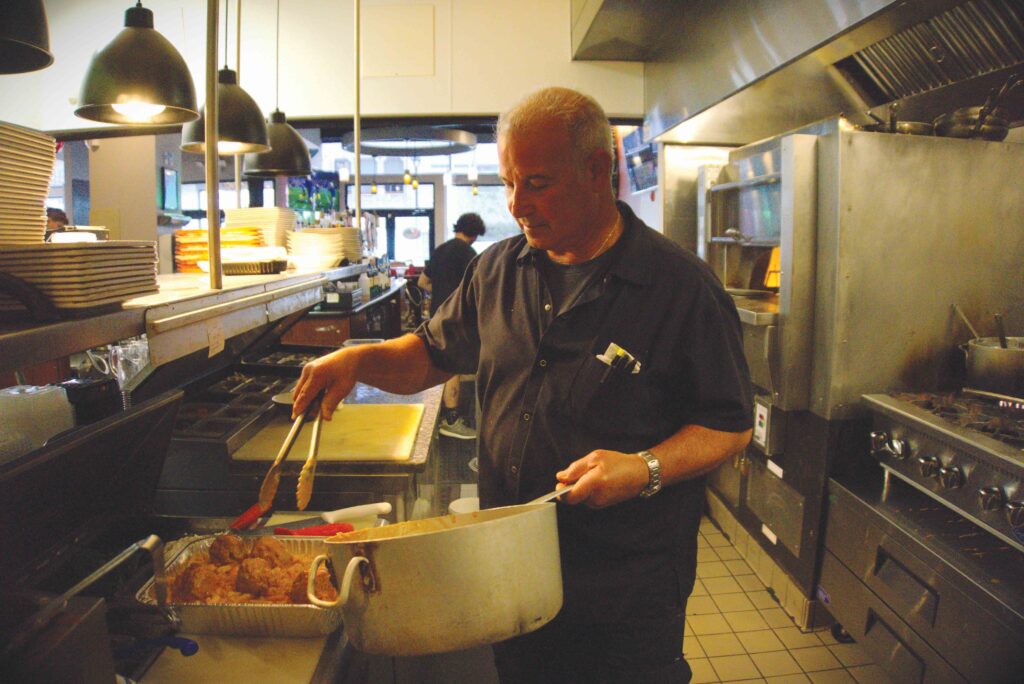 Image of Vernon using tongs to place cutlets in a pan.