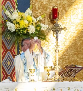 Sunlight hits the Eucharist as bishop bonnar prays the Eucharistic Prayers at the Assumption Pilgrimage in North Jackson