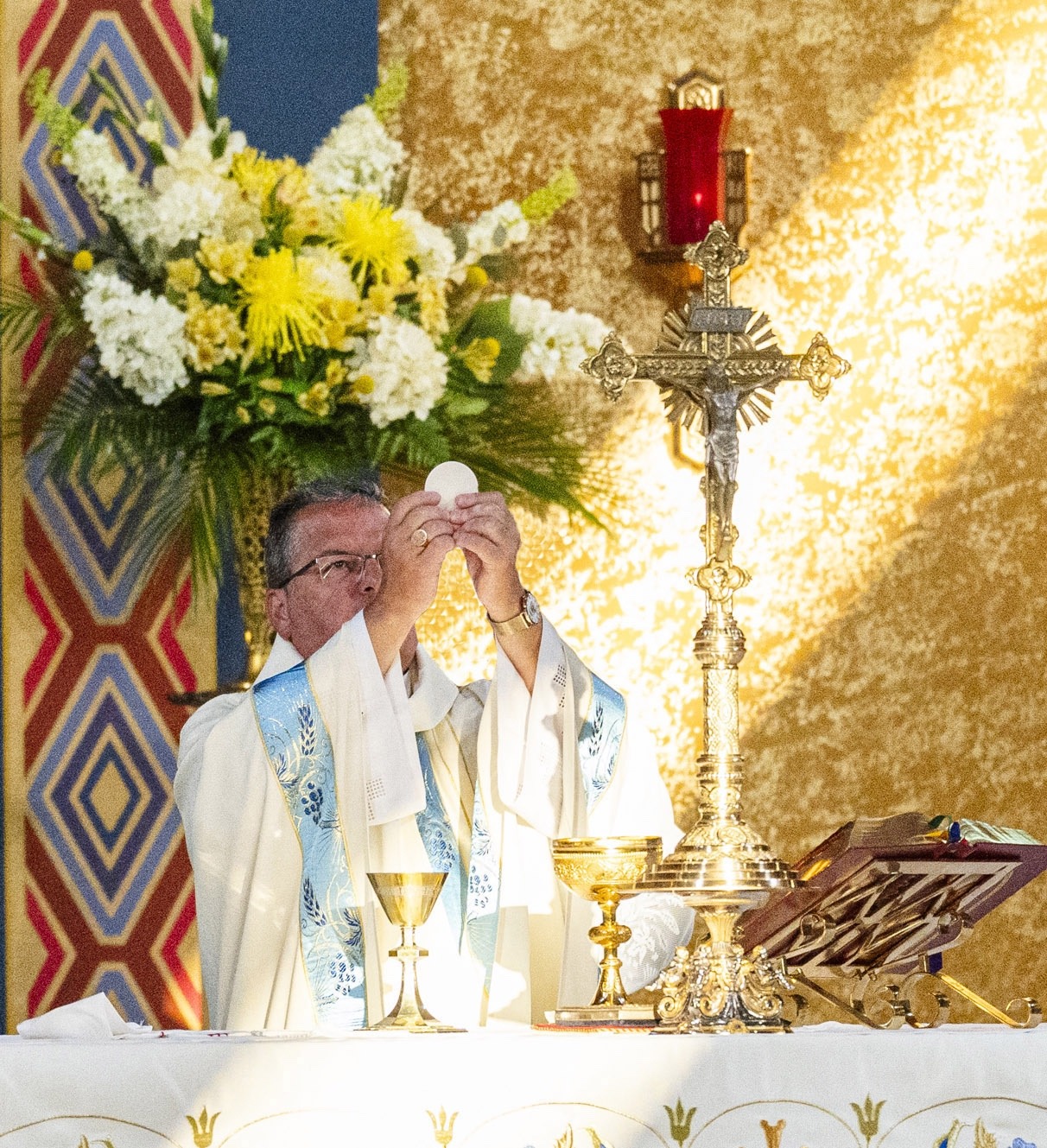 Sunlight hits the Eucharist as bishop bonnar prays the Eucharistic Prayers at the Assumption Pilgrimage in North Jackson