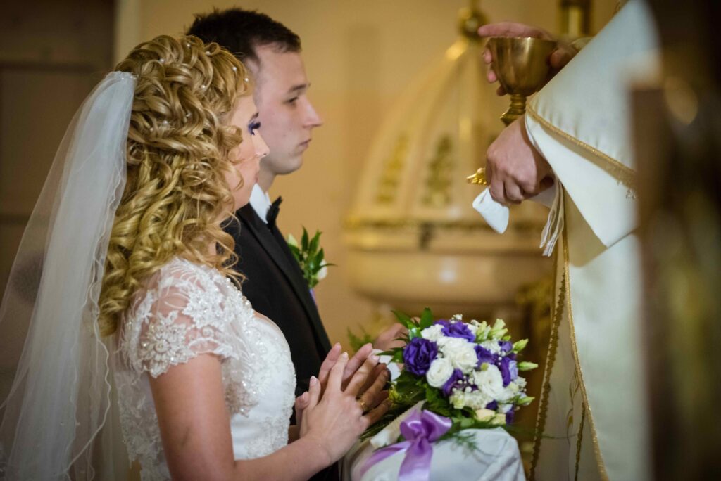 Bride and groom kneel before a priest