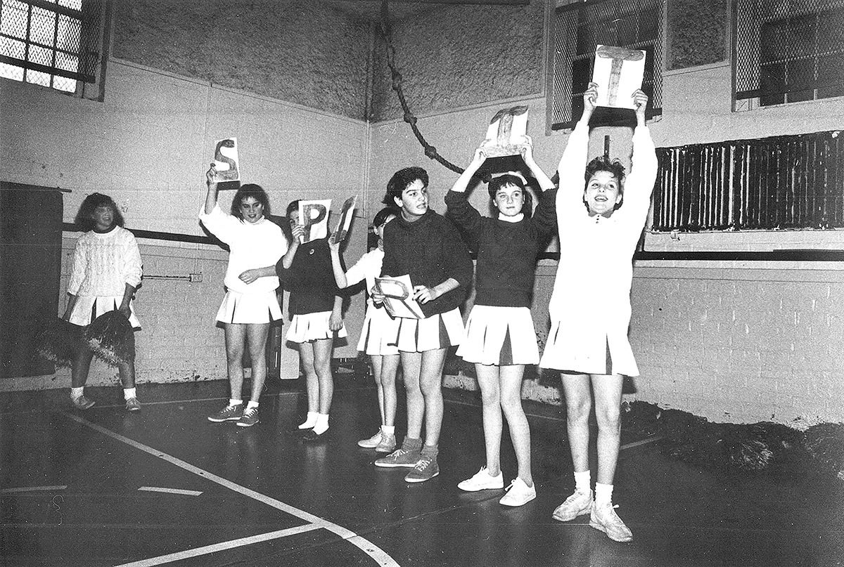 Black and white photo of cheerleaders holding signs that read SPIRIT