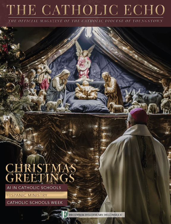 Cover of December 2024 issue, featuring Bishop Bonnar kneeling before a nativity scene