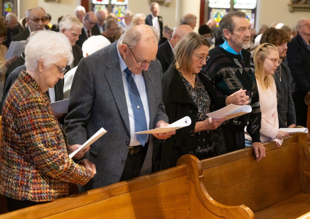 Two couples stand in the first pew during the anniversary celebration