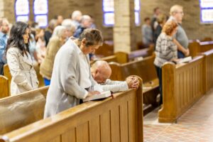 Parishioners kneel in prayer during Mass at St. Michael the Archangel