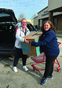 Two women hold a box full of catholic charities donations