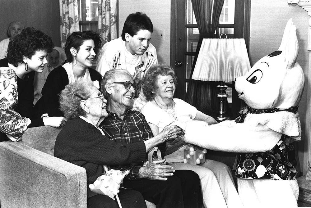 historical photo showing a child dressed as the Easter Bunny, entertaining residents of a senior center