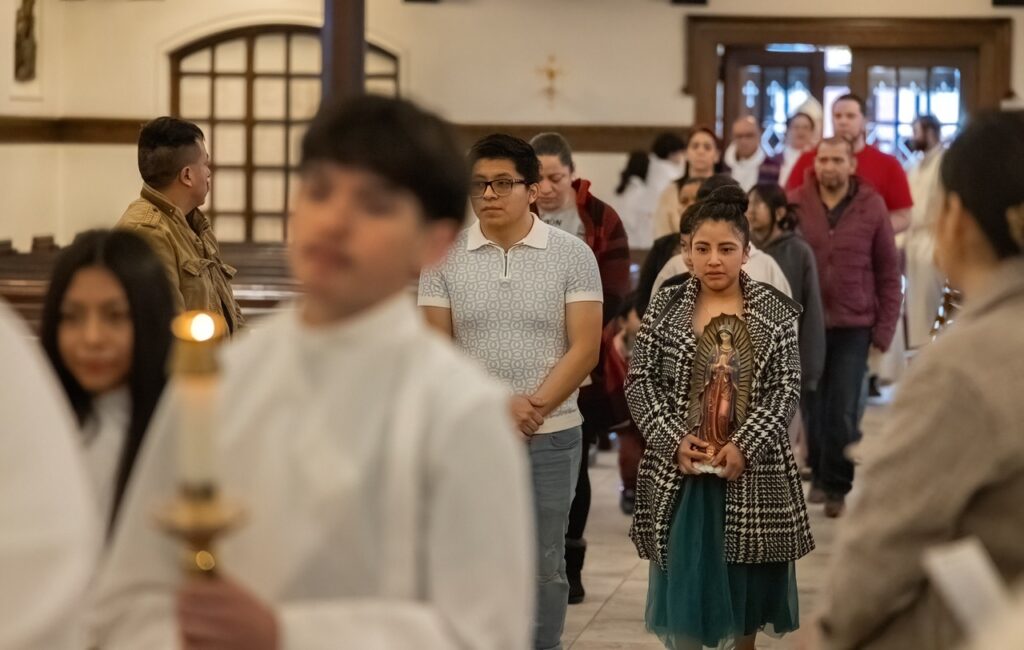People walk in procession, holding a statue of Our Lady of Guadalupe. Photo by Bob Rossiter