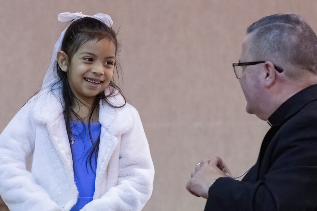 Bishop smiles at young girl during Hispanic Conference 2025. Photo by Bob Rossiter