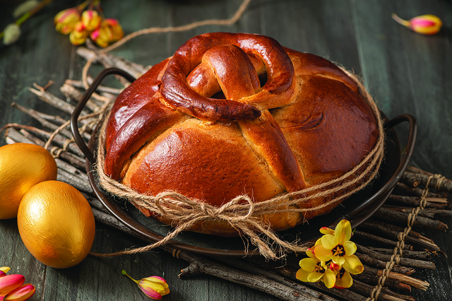Portuguese traditional Easter cake. Folar with golden eggs on easter table. Blossom flowers and golden painted eggs.