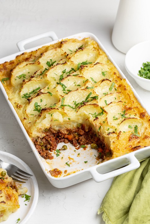 English Shepherd's pie, or cottage pie, or French version hachis Parmentier. Cooked minced beef meat with vegetables, green pea, carrot, onion, topped with mashed potato with cheese and baked. Vertical image.
