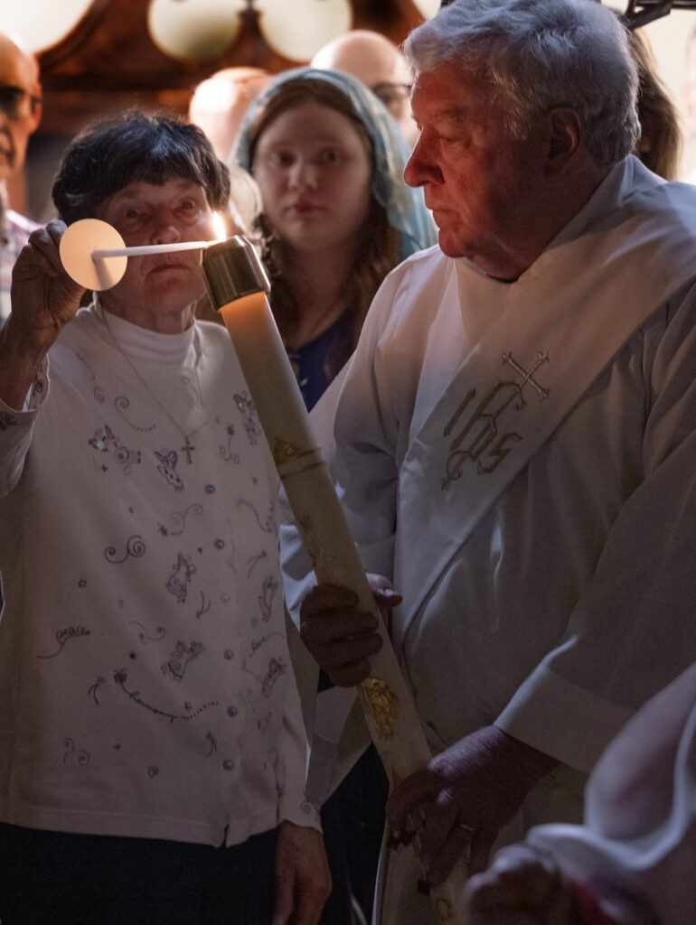 Parishioners light their candles from the Easter fire at St Ann.