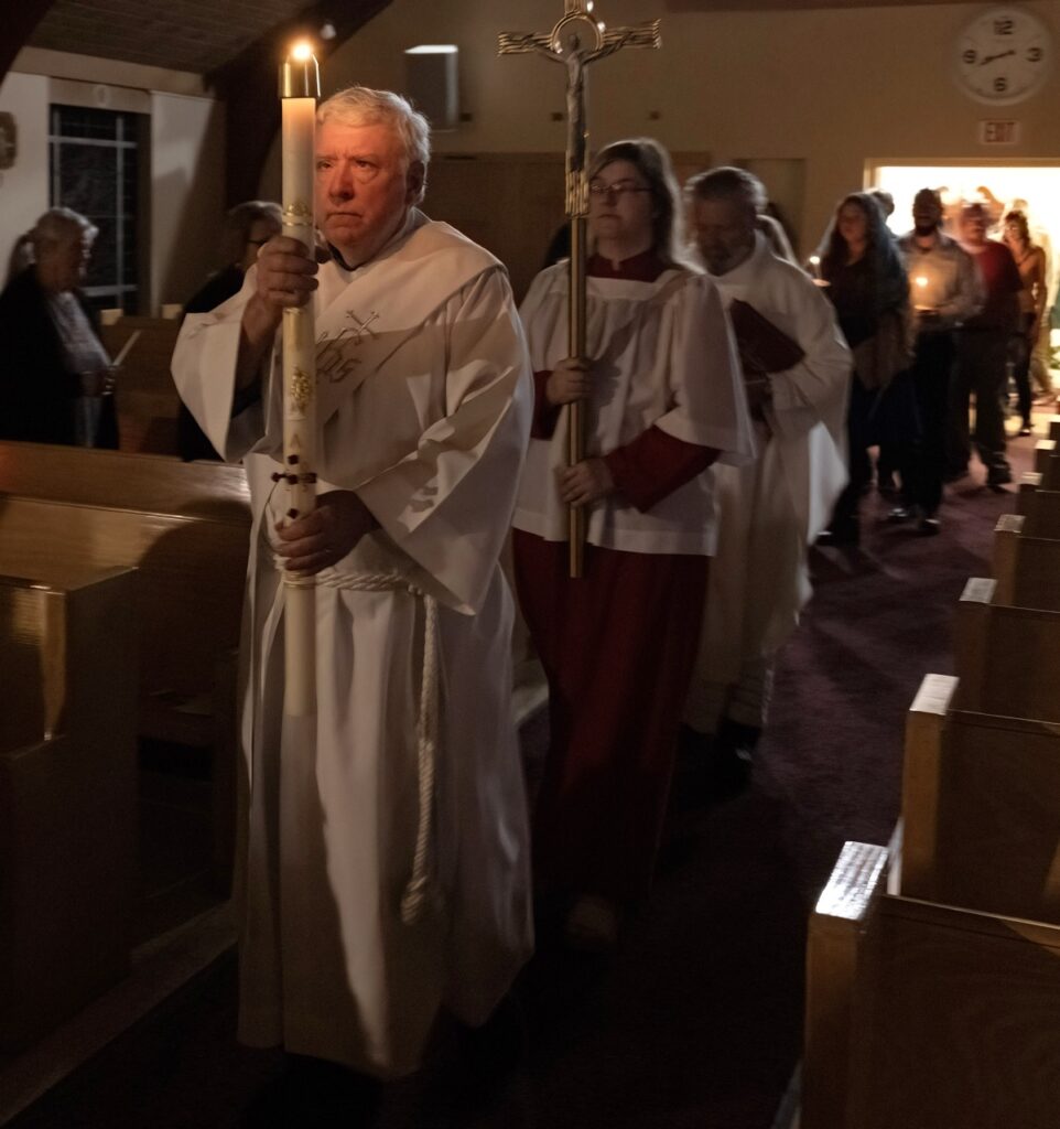 Servers walk in procession with the Easter flame at St. Anns