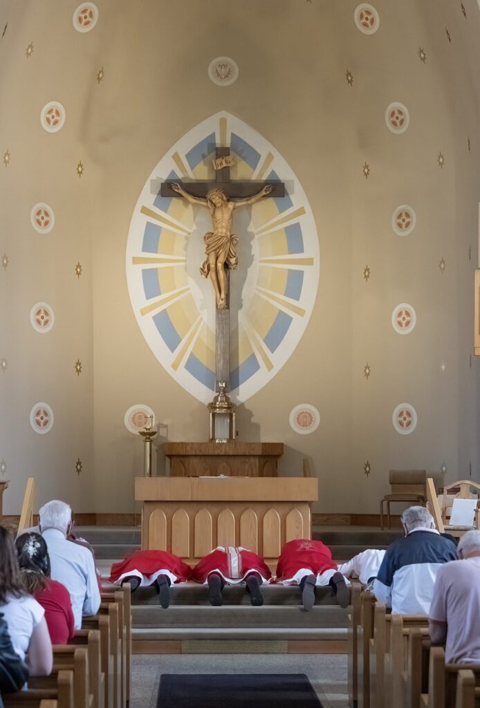 Image of priests lying prostrate on the altar at Holy Family in Navarre on Good Friday. Photo by Bob Rossiter.