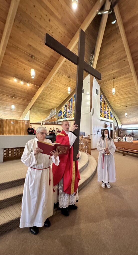 Father holds the cross high at Our Lady of Peace Parish in Ashtabula during Good Friday. Photo by Marilou McClimans.