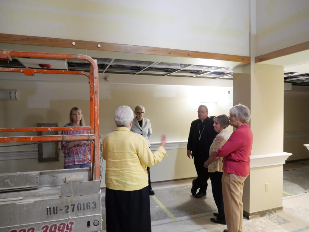 Bishop Bonnar stands in a construction zone and listens to the gathered sisters about their renovations. Photo by Michael Houy