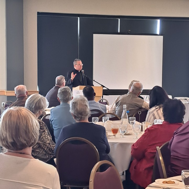 Bishop David Bonnar speaks to an audience gathered around lunch tables