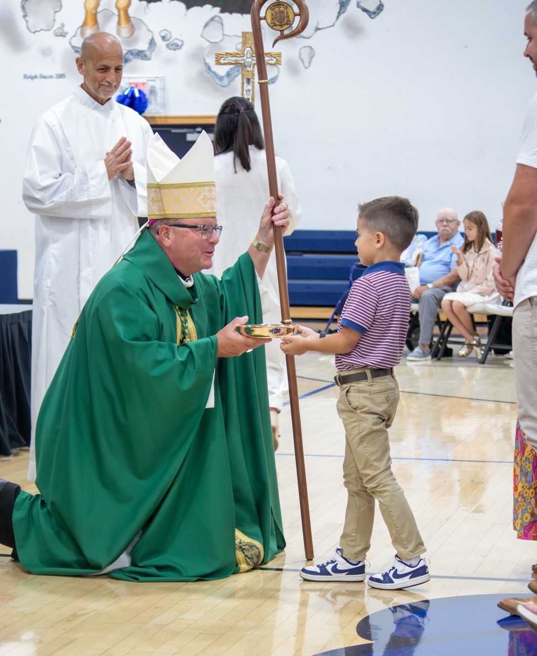 Bishop Bonnar accepts the gifts off a young child at the Mass at St. John School's ribbon cutting