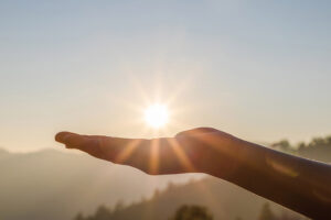 A hand holding the sun at dawn.
