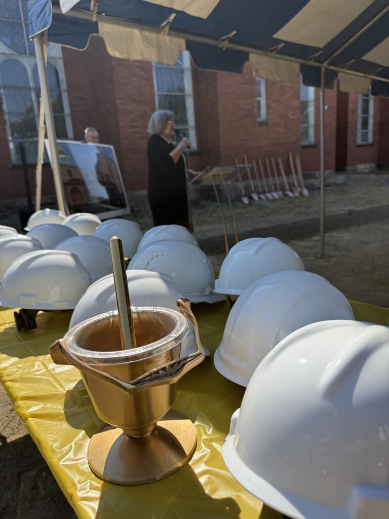 A pail of holy water sits next to hardhats