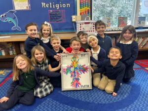 Kids hold up a painting of a cross