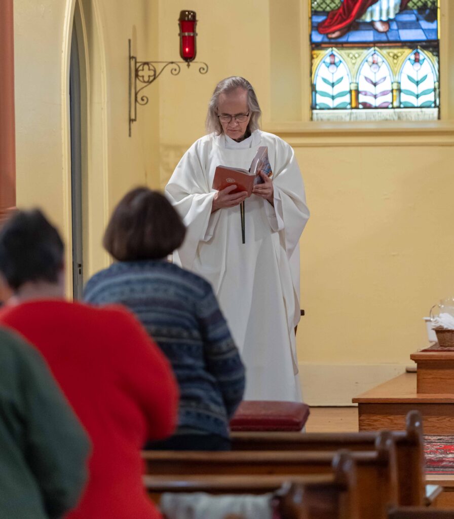 Father Wassie reads from a bible