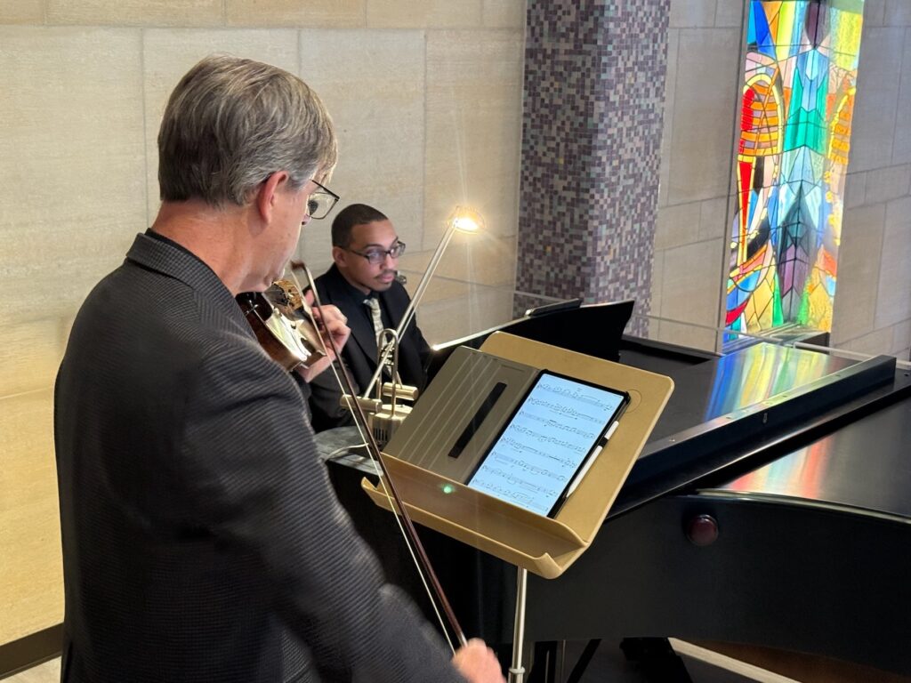 ralph holtzhauser plays the piano, accompanied by a violinist