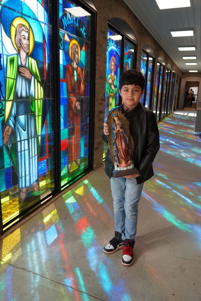 A young boy holds an Our Lady of Guadalupe statue. Photo by Paulina Montaldo.