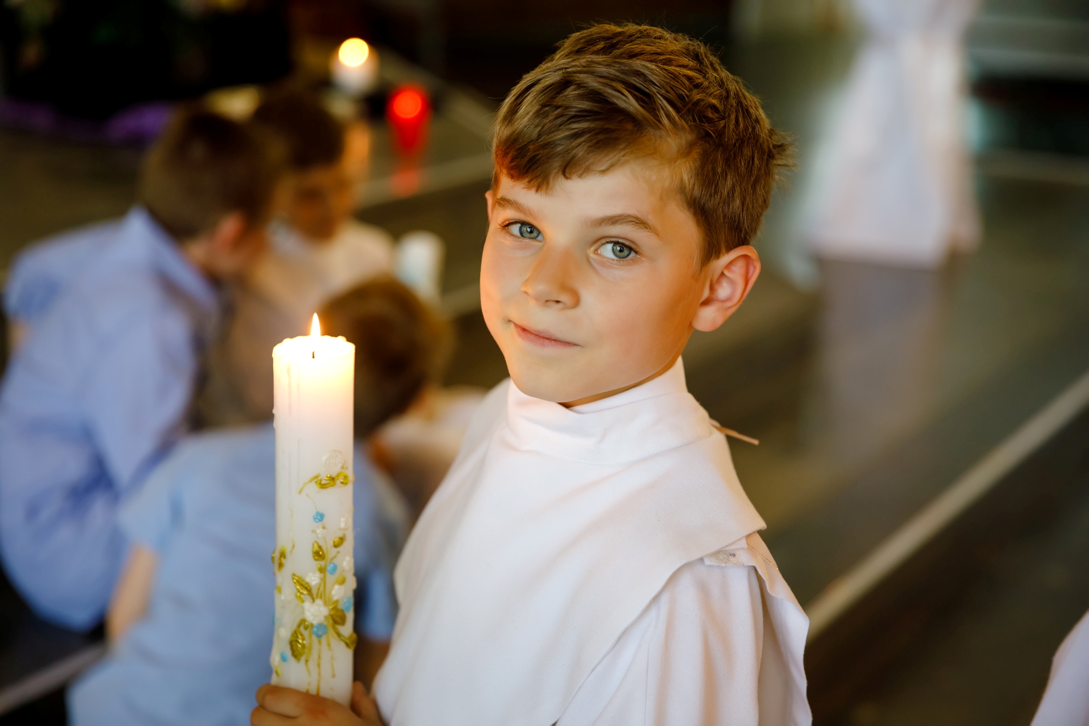 Catholic boy holding a First Communion candle, symbolizing a young Catholic’s journey of discerning his vocation.