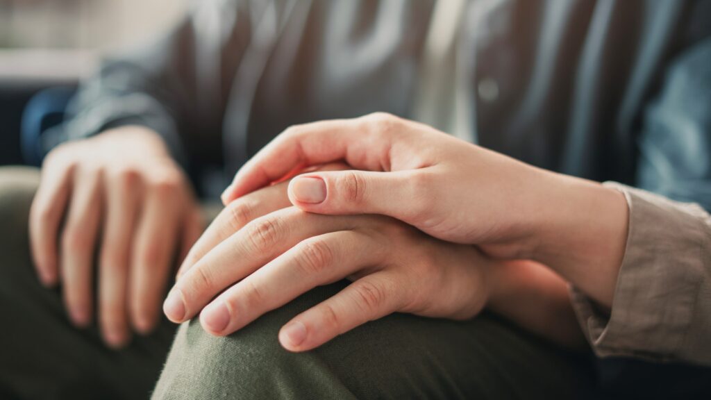 A woman comforts someone with her friendship by placing her hand over his.
