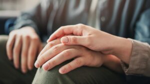 A woman comforts someone with her friendship by placing her hand over his.